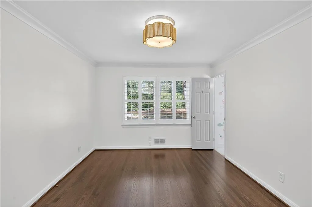 Unfurnished room featuring dark wood-style flooring and crown molding