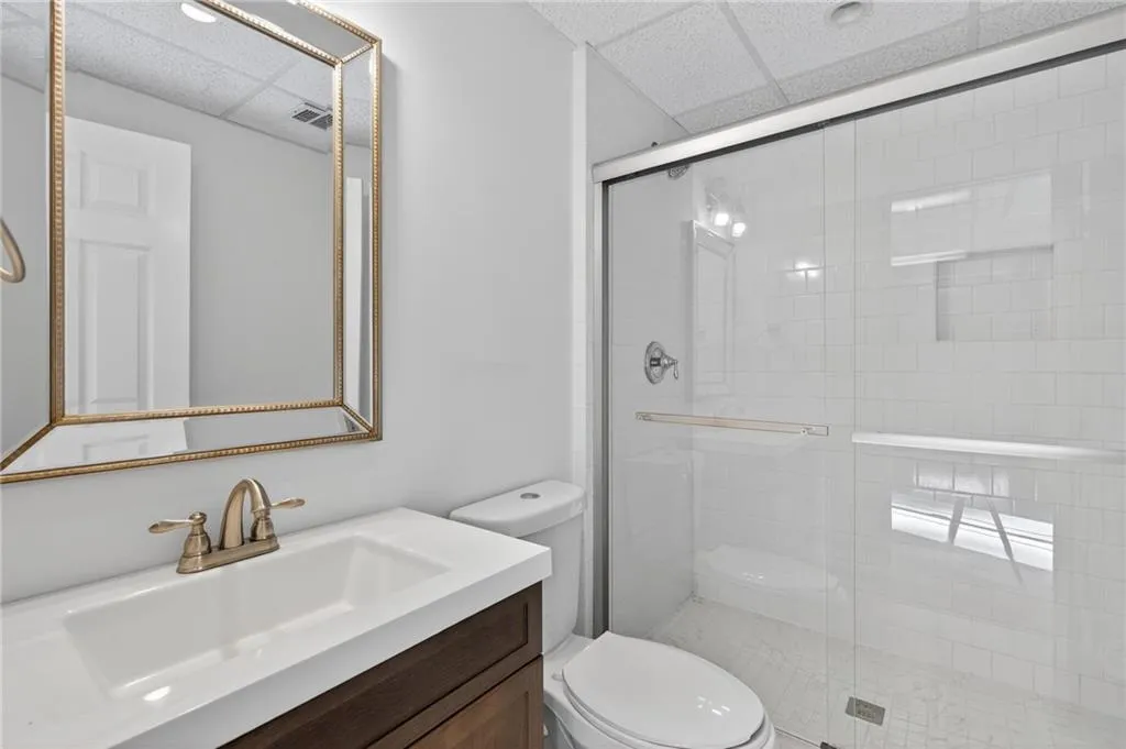 Bathroom with a drop ceiling, vanity, and a stall shower