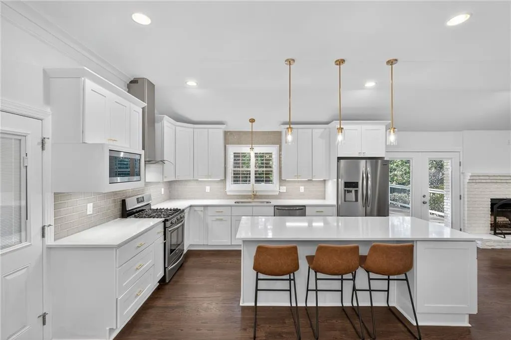 Kitchen featuring decorative backsplash, appliances with stainless steel finishes, a breakfast bar, white cabinets, and a kitchen island