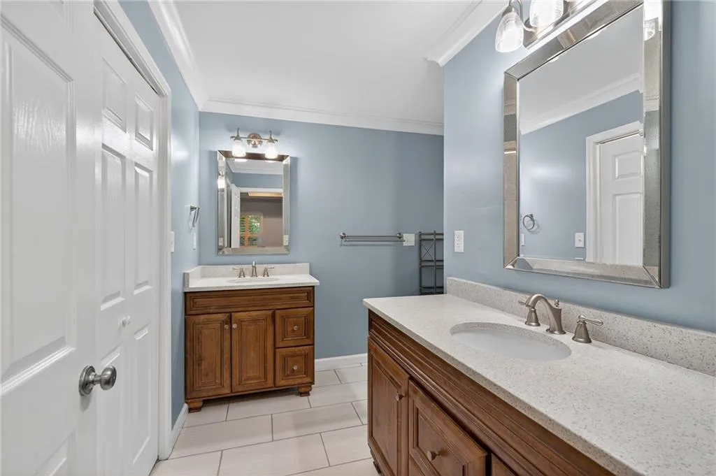Bathroom with two vanities, crown molding, and light tile patterned flooring