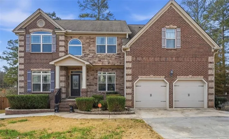 Traditional home with driveway, a garage, brick siding, and a front lawn