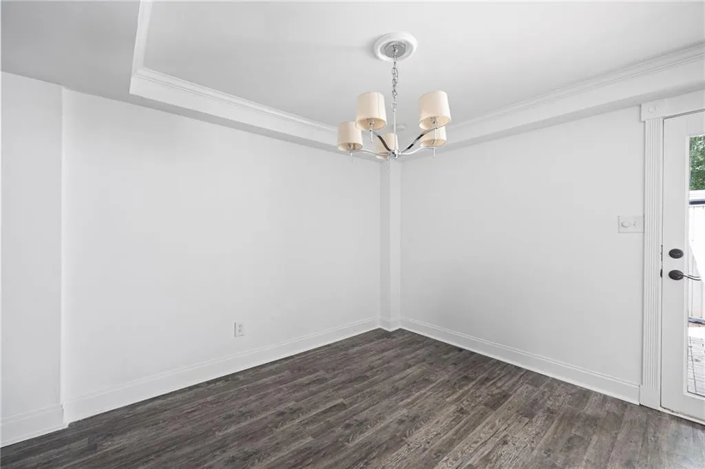 Unfurnished room featuring crown molding, an inviting chandelier, and dark hardwood / wood-style flooring