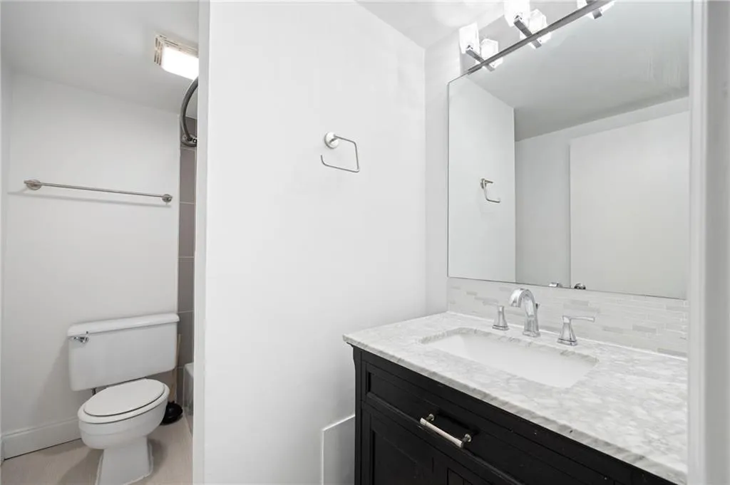 Bathroom with tile patterned flooring, backsplash, vanity, and toilet