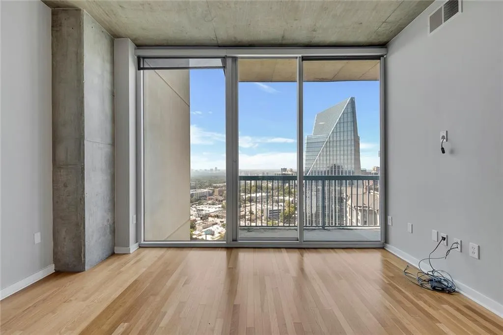 Hardwood flooring, floor-to-ceiling sliding glass doors, exposed concrete ceiling, and exposed concrete structural column