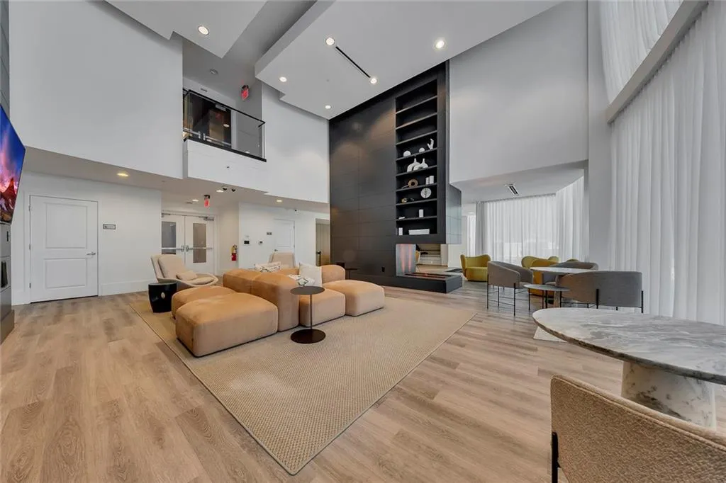 Spacious lounge area featuring wood-finish flooring, a contemporary fireplace with integrated shelving, and recessed lighting