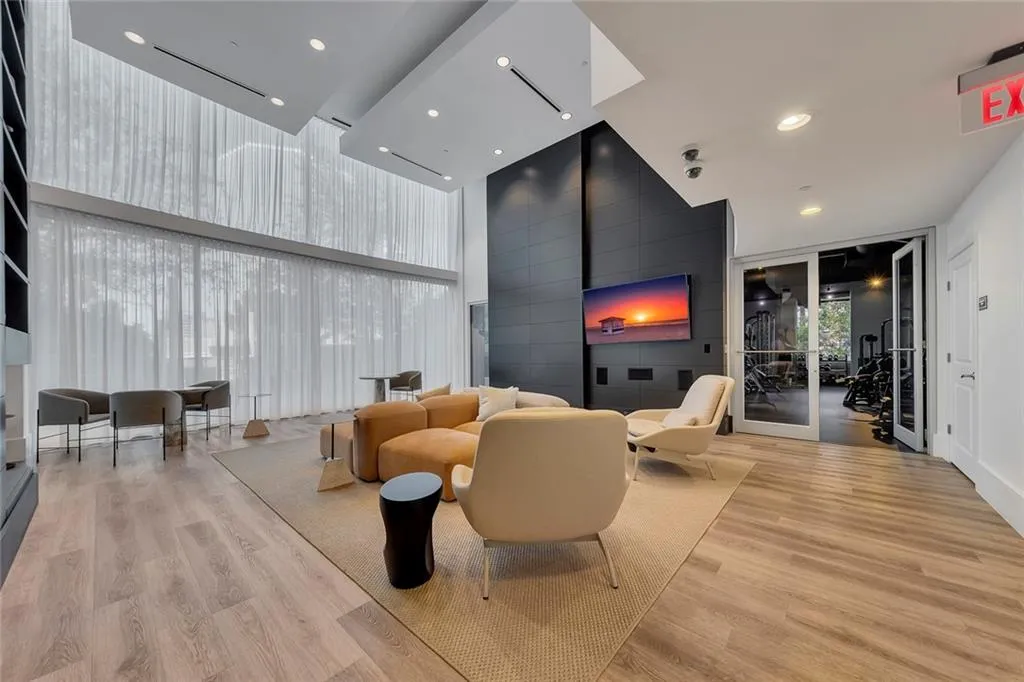 Expansive wall of windows with sheer drapery, recessed lighting, wood-finish flooring, and a mounted flat-screen television