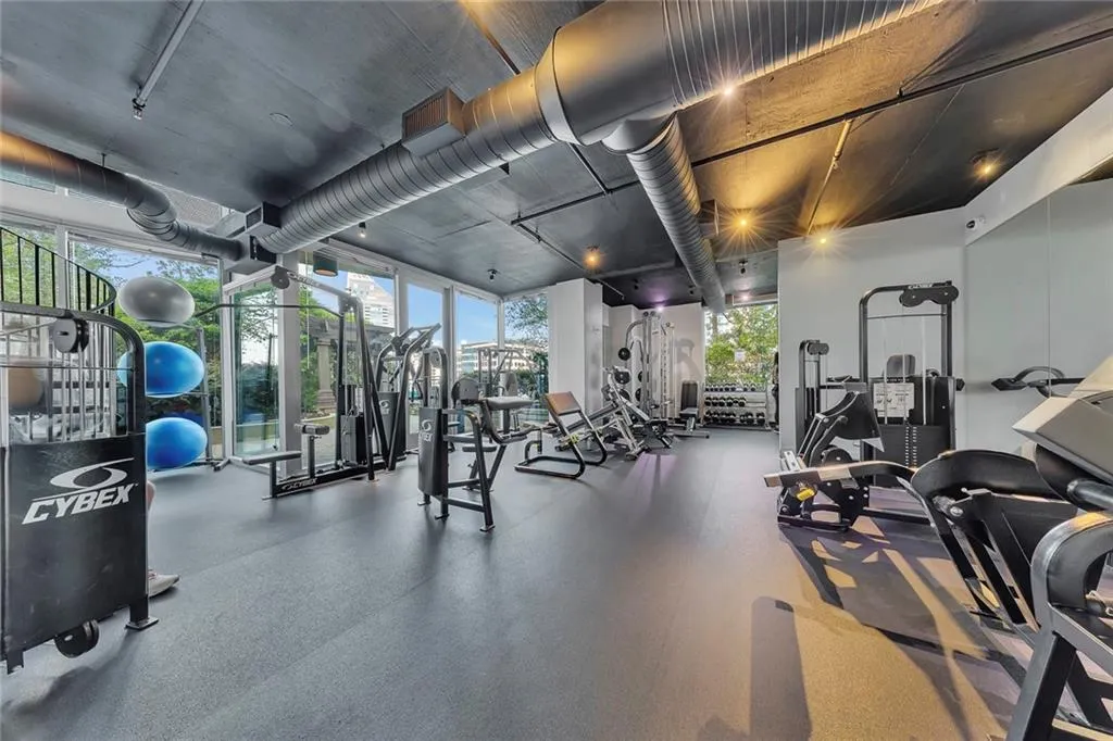 Dedicated fitness space featuring a rubberized floor, exposed ceiling ducts, recessed lighting, and expansive floor-to-ceiling windows