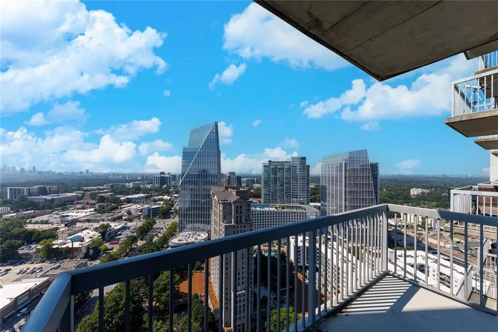 Balcony with metal railing and concrete flooring overlooking a cityscape with multiple high-rise buildings
