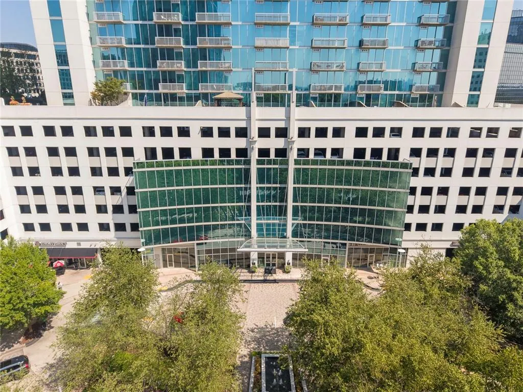 Modern high-rise with a multi-level facade, featuring expansive glass balconies and a prominent entrance canopy