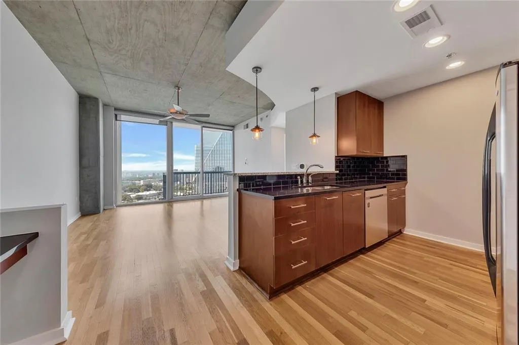 Hardwood flooring throughout, modern kitchen with stainless steel appliances, dark stone countertops, and subway tile backsplash