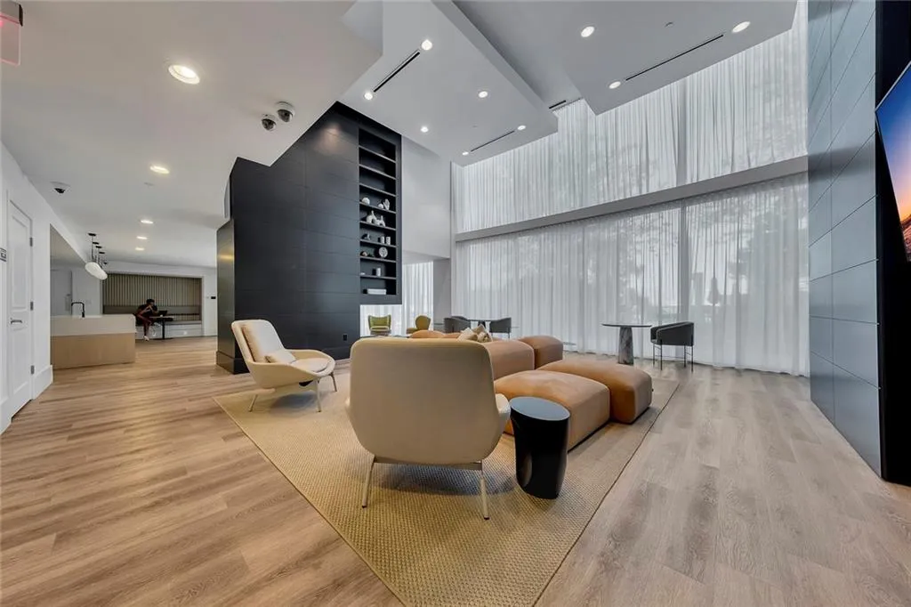 Double-height windows with sheer drapery, recessed lighting, wood-finish flooring, built-in shelving, and a built-in countertop