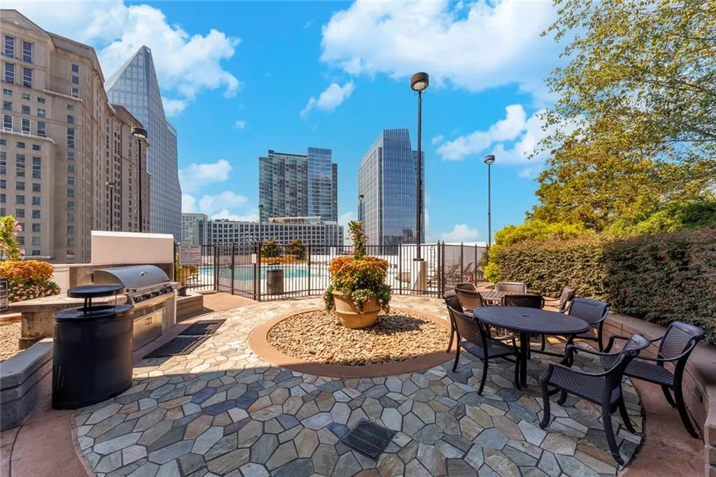 Stone paver patio featuring a built-in outdoor grill station, a perimeter of decorative gravel, and a fenced swimming pool area