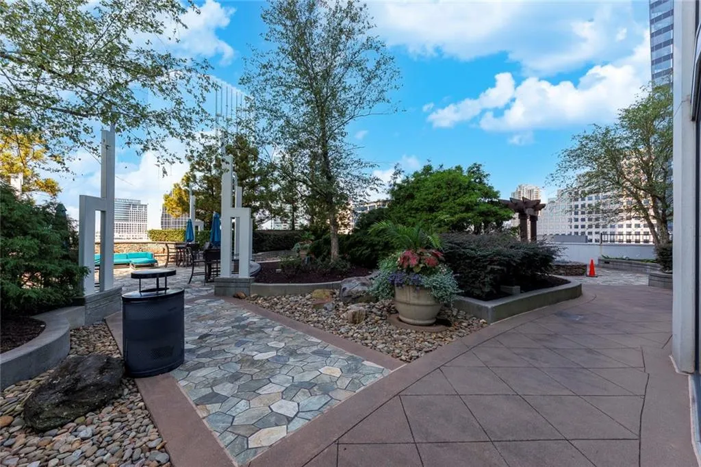 Expansive outdoor terrace featuring varied paving, mature landscaping, and an open pergola
