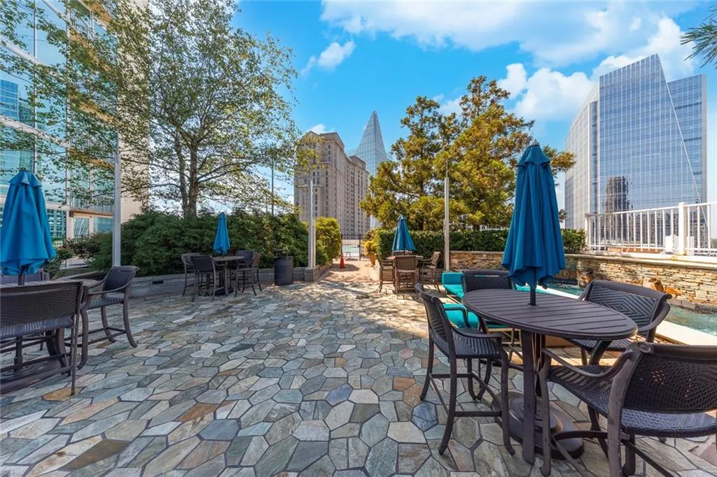 Patio area featuring irregular stone paving, mature trees, and a stone-clad water feature
