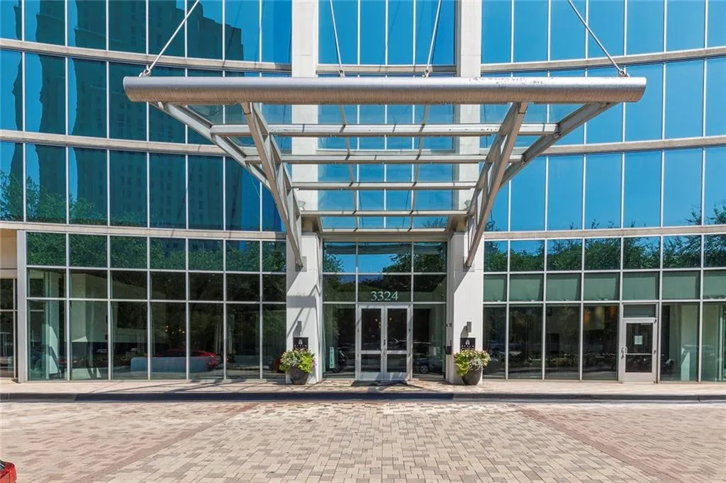 Modern glass facade with a curved design, featuring a prominent metal porte-cochere