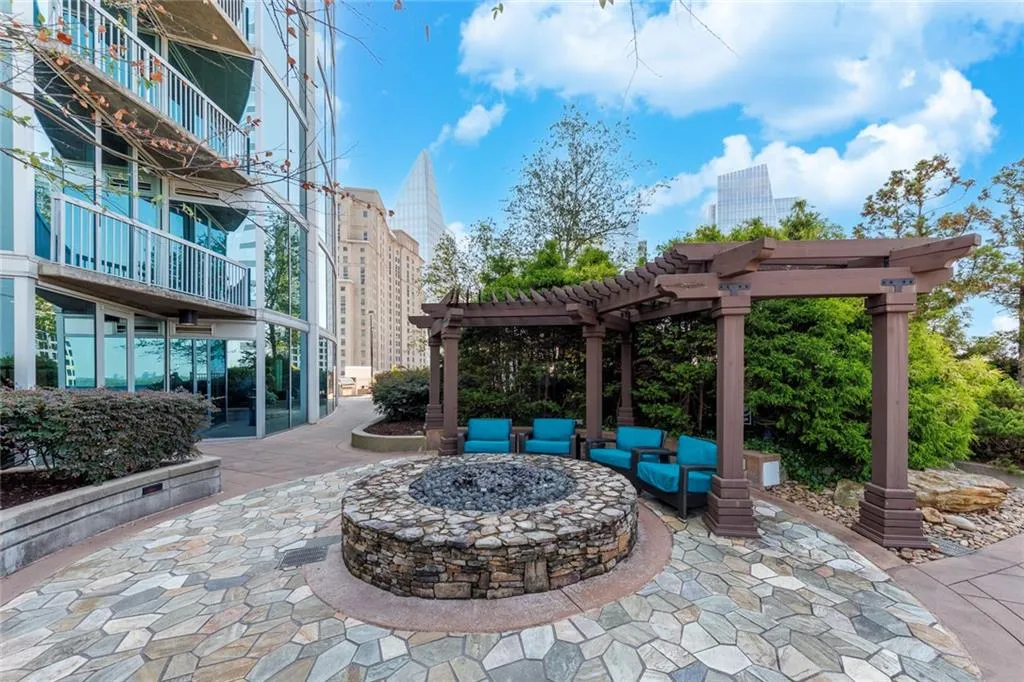 Stone-faced fire pit with a flagstone patio, surrounded by a dark wood pergola