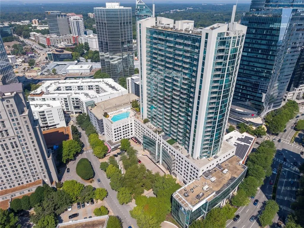 Modern high-rise residential building with balconies, an adjacent building with a rooftop pool, and surrounding urban architecture