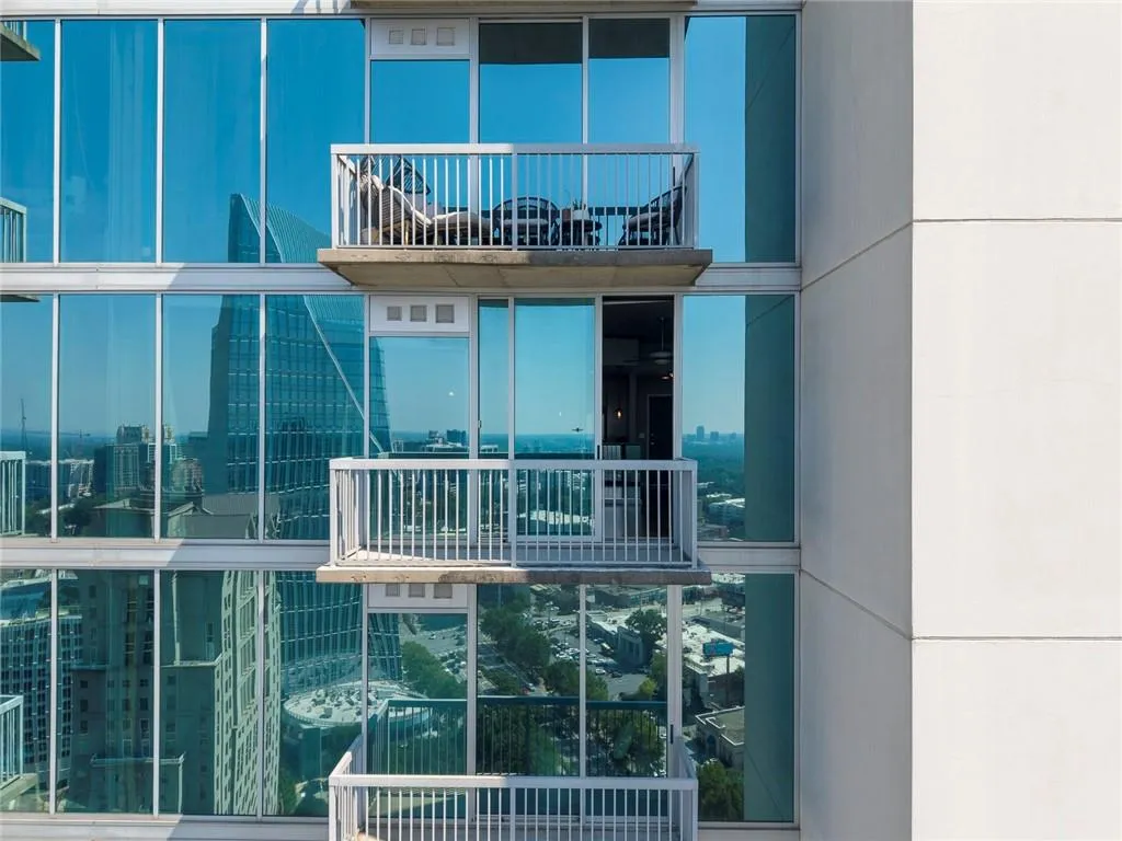 Floor-to-ceiling glass windows and multiple private balconies with white railings