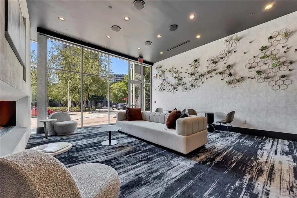 Full-height window wall with extensive glazing, recessed ceiling lighting, textured wall finish with decorative paneling, and an integrated built-in fireplace