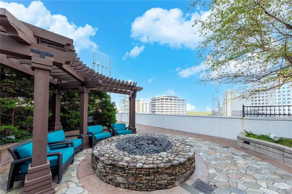 Outdoor patio featuring a stone fire pit, flagstone paving, and a slatted pergola structure
