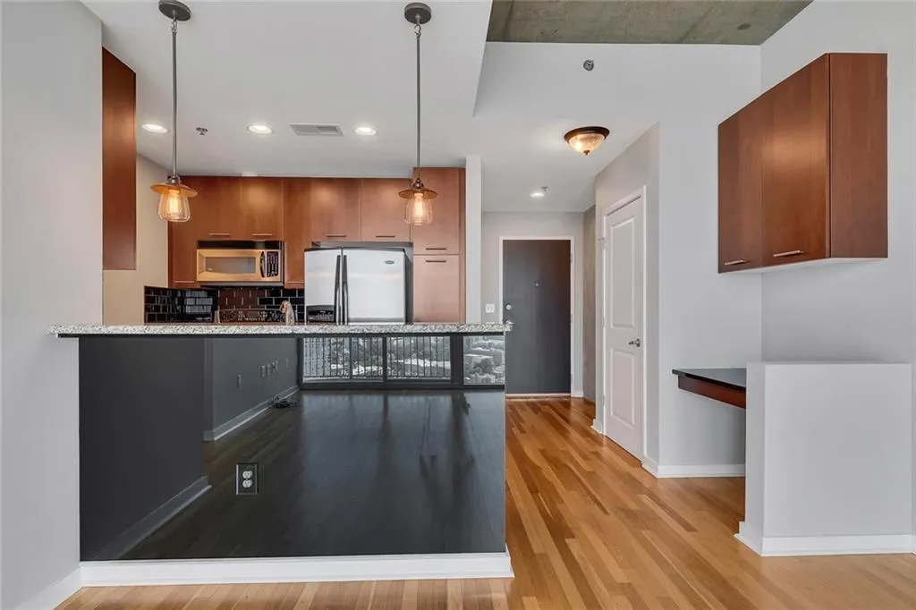 Kitchen featuring wood-finish cabinetry, stainless steel appliances, a tile backsplash, and a breakfast bar with pendant lighting