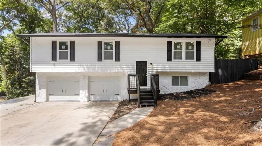 Split-level residence featuring white siding and a dark roof
