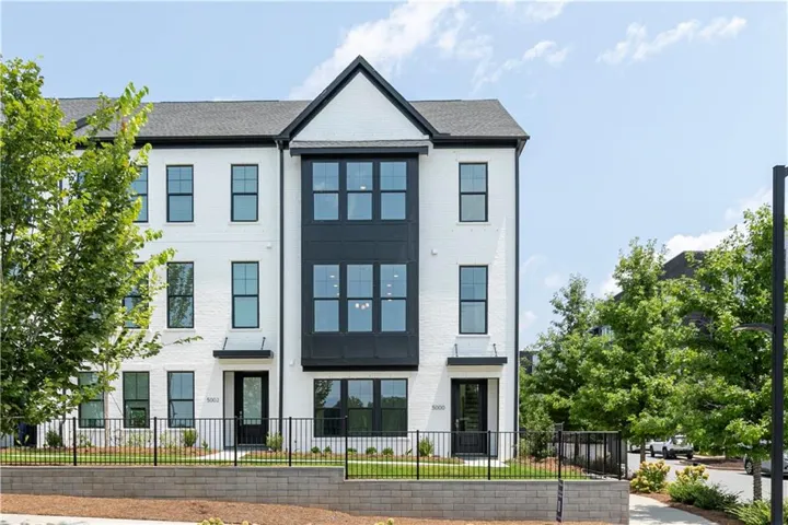 Modern townhome exterior featuring a white brick facade and dark contrasting accents