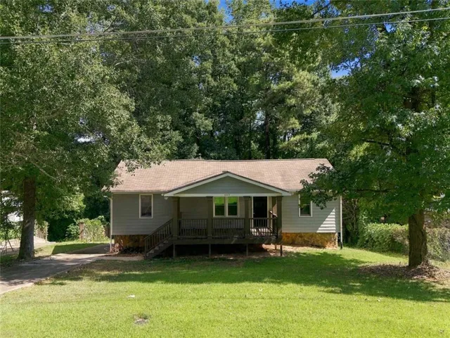 Siding exterior with stone foundation detailing, covered front porch, and mature trees