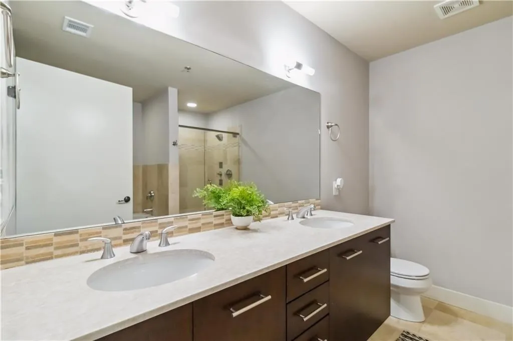 Full bath featuring tasteful backsplash, a shower stall, double vanity, and tile patterned floors