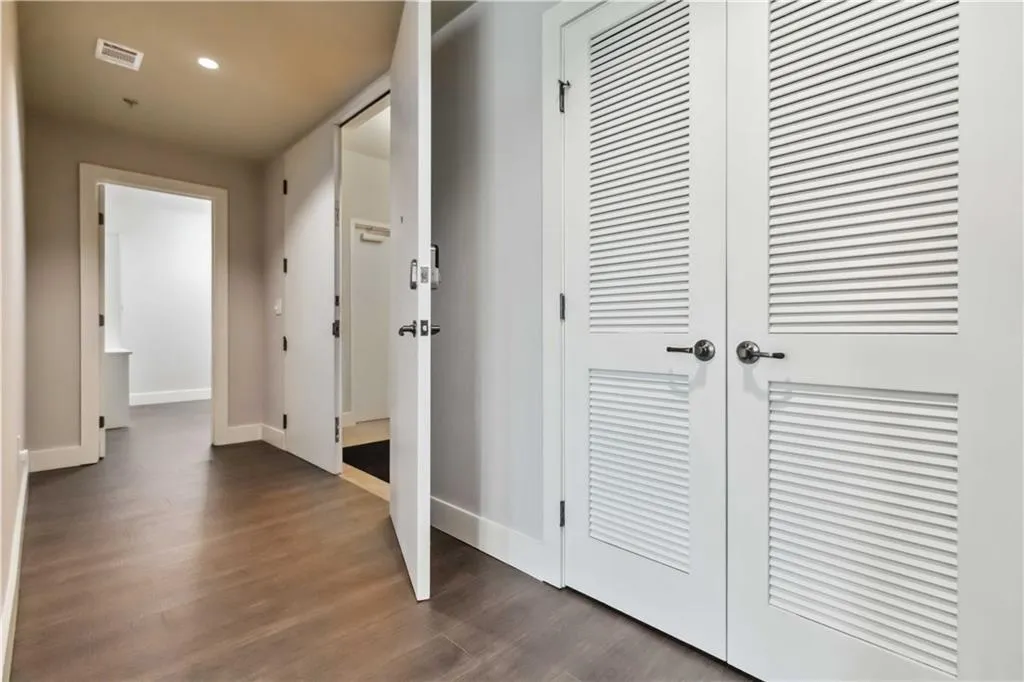 Hall with dark wood-type flooring and recessed lighting