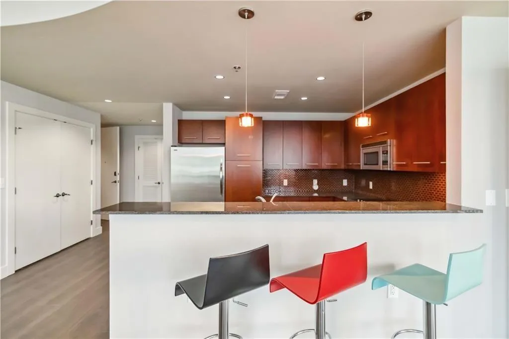 Kitchen with stainless steel appliances, tasteful backsplash, dark stone countertops, a peninsula, and pendant lighting