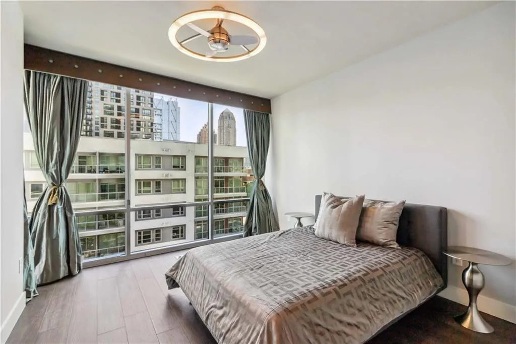 Bedroom featuring a wall of windows, wood finished floors, and a city view