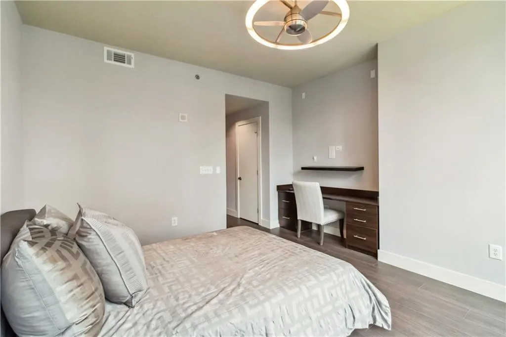 Bedroom with dark wood finished floors and built in study area