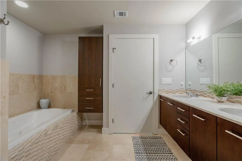 Full bathroom featuring double vanity, a bath, tile patterned floors, and decorative backsplash