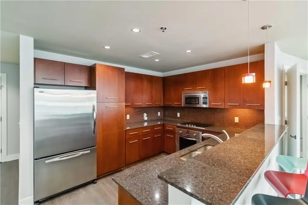 Kitchen featuring appliances with stainless steel finishes, tasteful backsplash, a peninsula, dark stone countertops, and recessed lighting