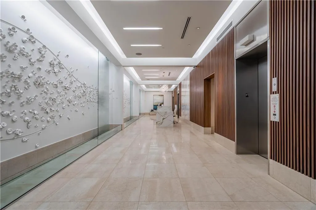 Hall featuring a raised ceiling, elevator, and wood walls