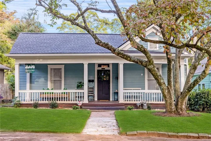 Charming exterior with light blue siding, a dark blue shingle roof, and a welcoming front porch