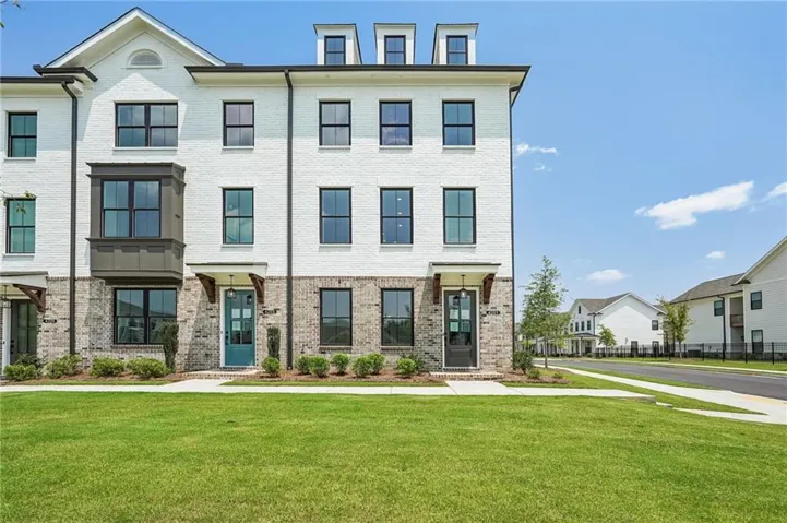 Contemporary townhome facade featuring white painted brick, a prominent bay window, and black-framed windows