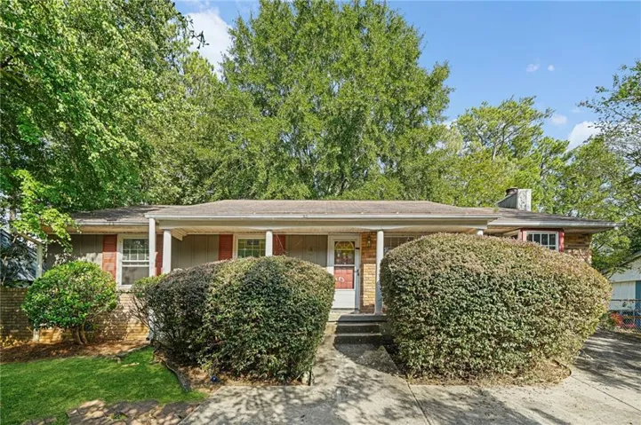 Ranch-style residence featuring a covered front porch with white columns, brick and siding exterior, and mature landscaping