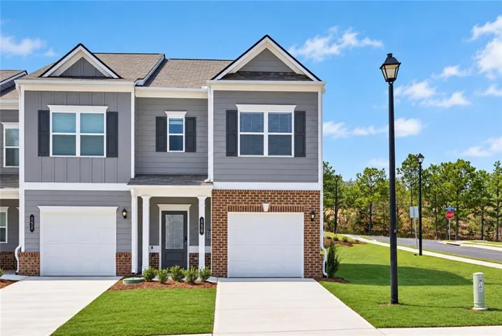 Multi-story exterior with a combination of brick and siding, featuring a covered entry and attached garage