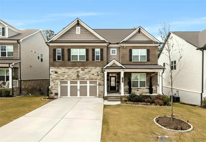 Craftsman-style home with stone siding, a front yard, and covered porch