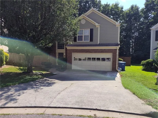 Two-story exterior with brick and siding facade, covered entry, and attached garage