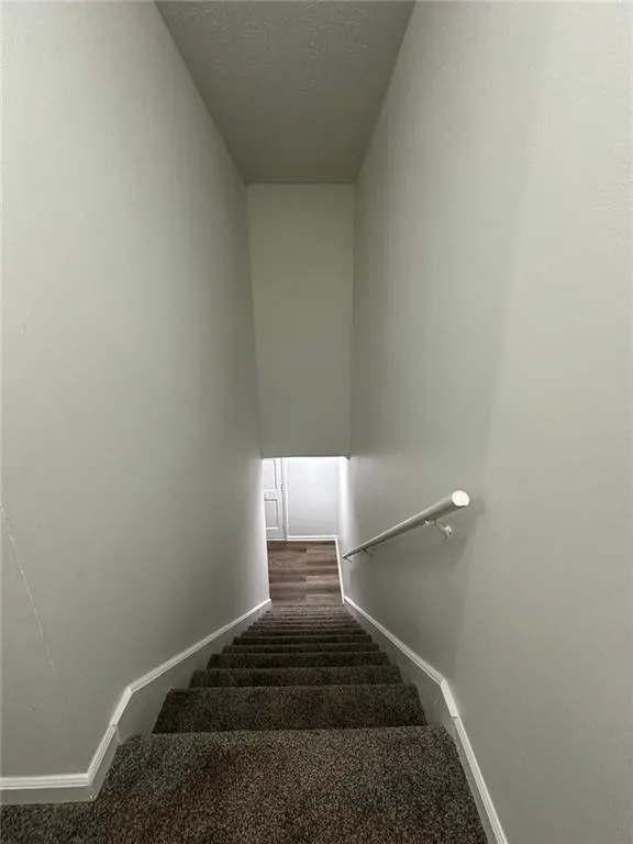 Stairs featuring carpet floors and a textured ceiling
