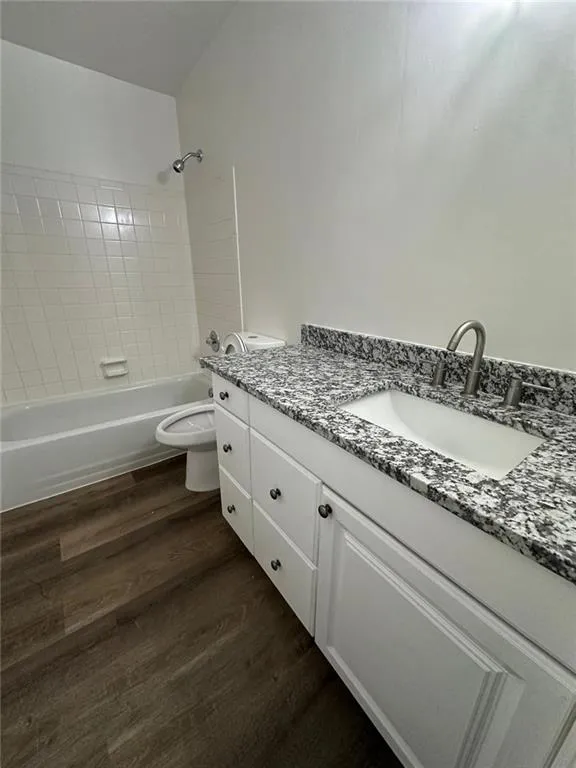 Full bathroom featuring wood-type flooring, toilet, tiled shower / bath, and vanity