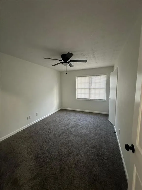 Carpeted empty room featuring ceiling fan