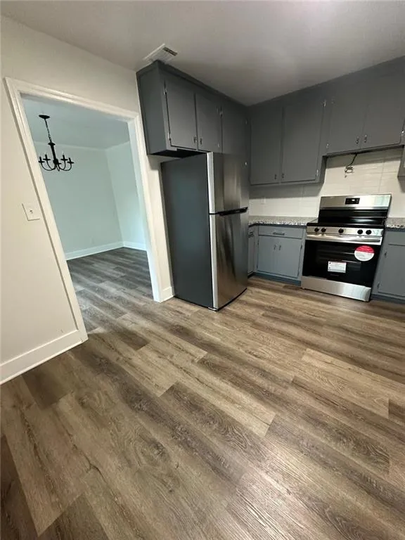 Kitchen featuring appliances with stainless steel finishes, a chandelier, dark hardwood / wood-style flooring, and gray cabinetry