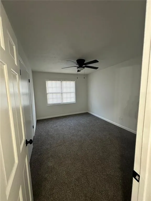 Carpeted empty room with ceiling fan