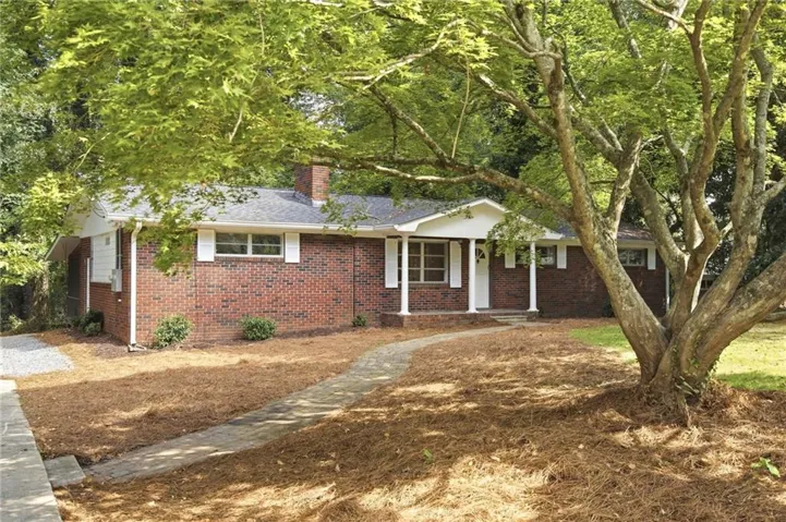 Charming brick ranch home featuring a covered front portico, multi-pane windows, and a brick chimney