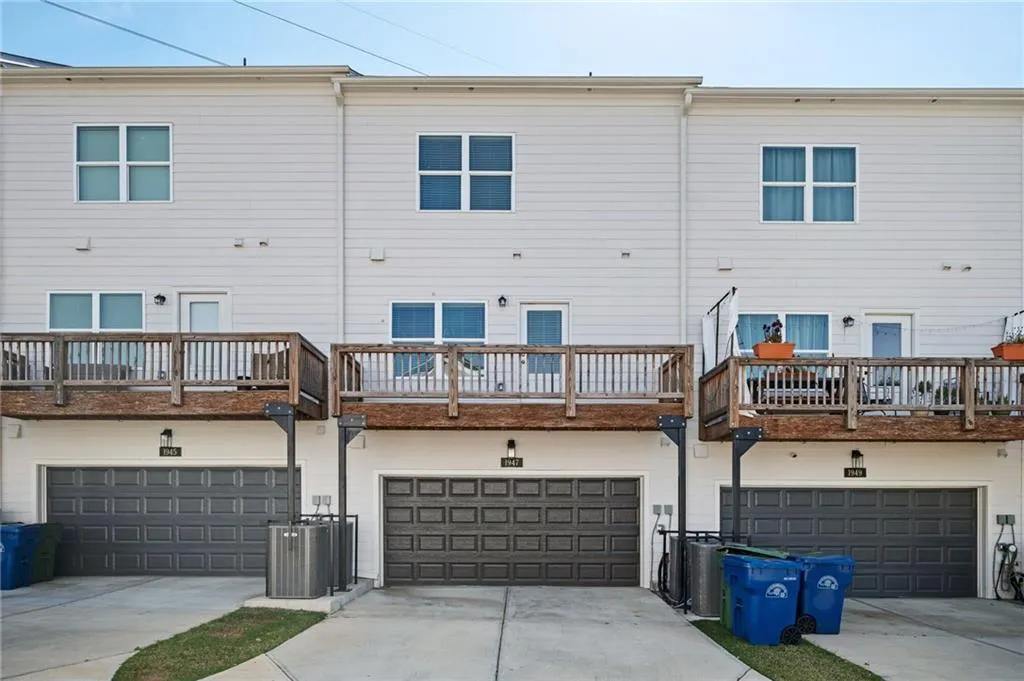 Rear view of property featuring a garage, driveway, and central AC