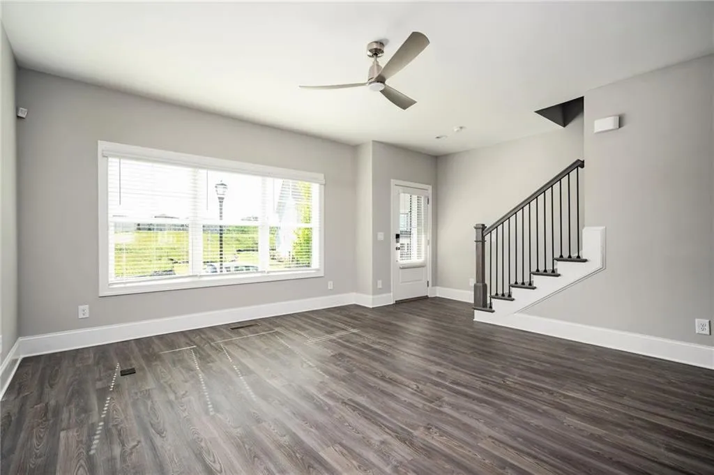 Entrance foyer featuring ceiling fan, dark wood-style flooring, baseboards, and stairs